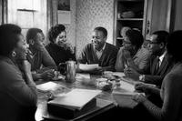 Vintage black and white photo of Black women and men gathered around a kitchen table, drinking coffee and talking together